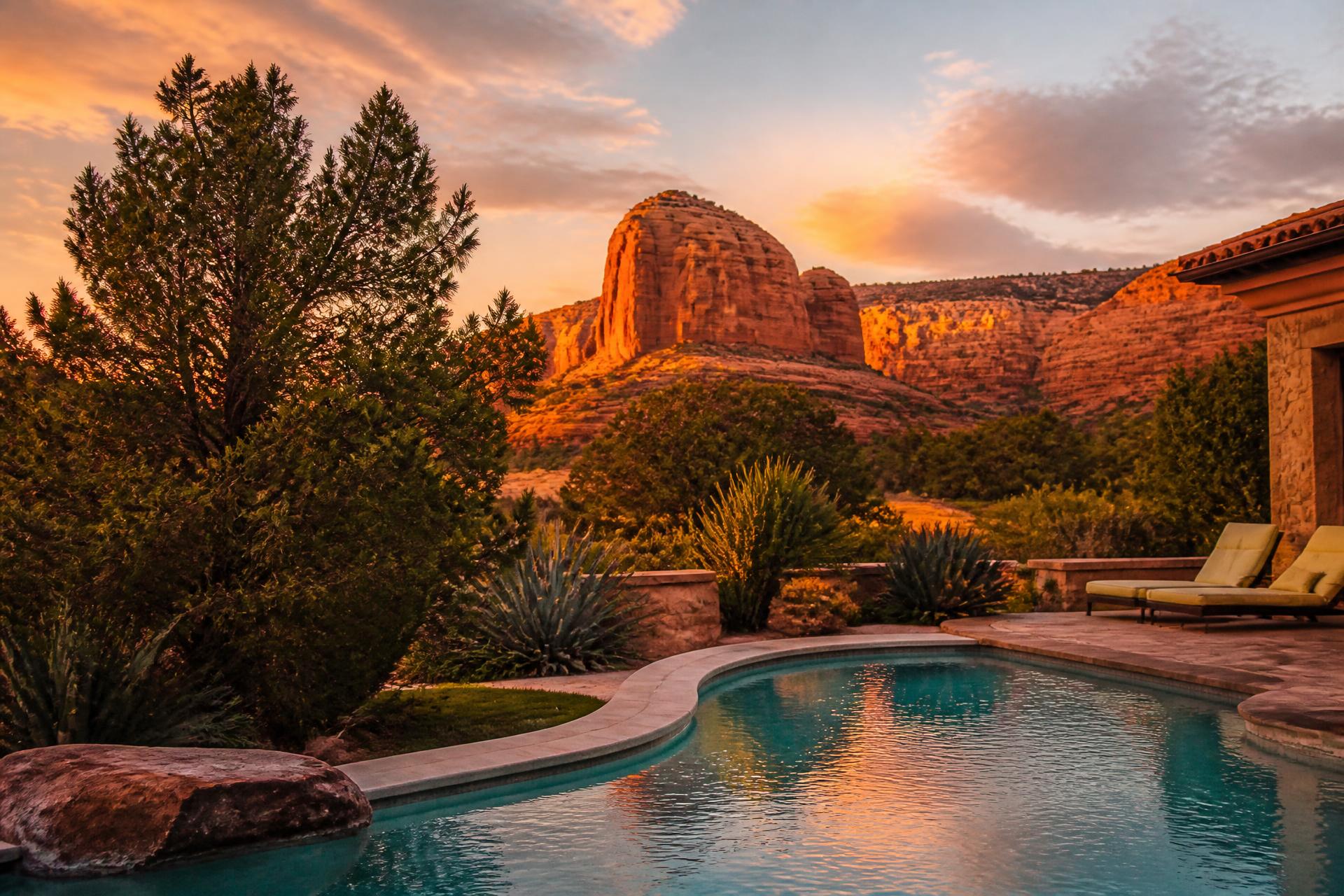 A luxury backyard swimming pool at golden hour with red rock buttes glowing in the Southern Utah desert